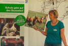 Elisabeth Deser zeigt ein Plakat mit Hühnern. 