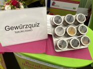 9 Gewürzdosen in einer Vorrichtung, daneben Schild mit Aufschrift Gewürzquiz