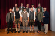Gruppenfoto Menschen in Trachtenmode vor rotem Vorhang