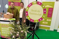 Zwei Personen hinter Standtisch neben Glücksrad