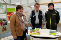 Drei Personen stehen an Messestand nebeneinander