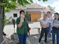 Frau mit Handpuppe steht neben Baum vor 3 Personen