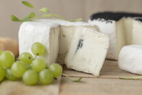 Weintrauben und runder Weichkäse, von dem ein Eck abgeschnitten ist